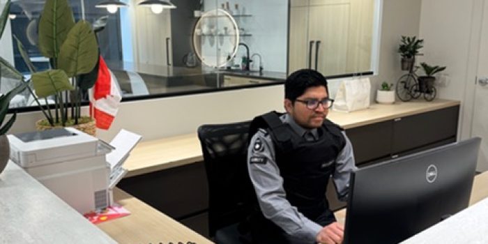 Nicagon concierge guard monitoring building access from the front desk of a modern lobby