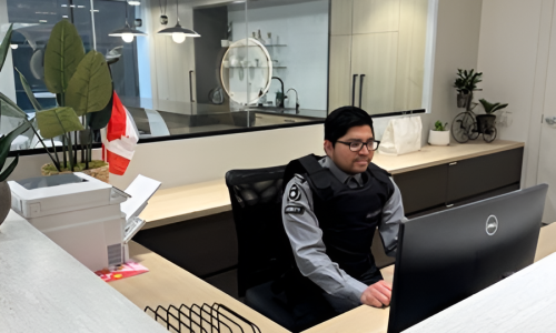 Nicagon concierge security guard working at a monitor behind a building reception desk