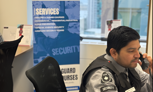 Nicagon security guard taking a call at the office desk beside the company banner