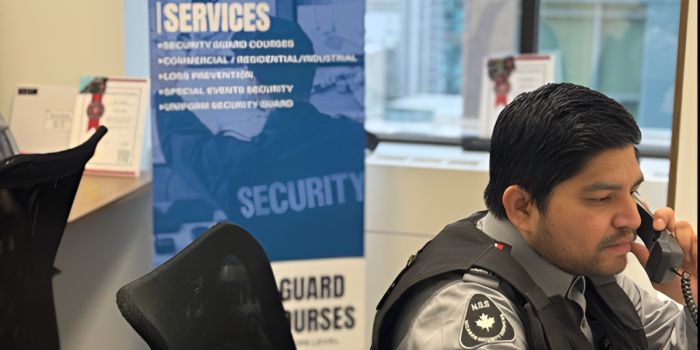 Nicagon security guard taking a call at the office desk beside the company banner