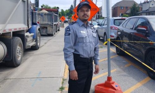 Nicagon traffic control guard directing vehicles beside a dump truck at a work site