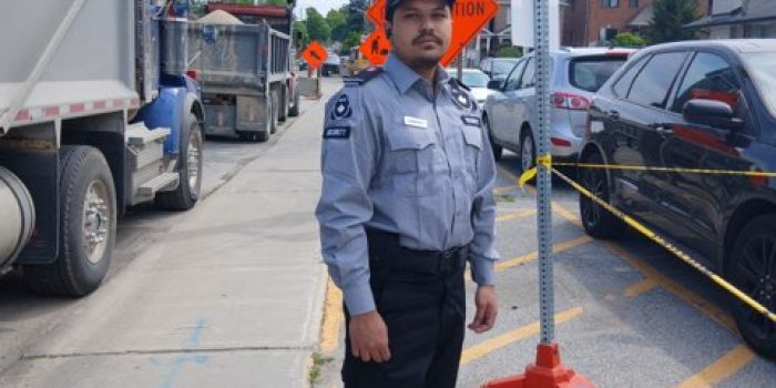 Nicagon traffic control guard directing vehicles beside a dump truck at a work site